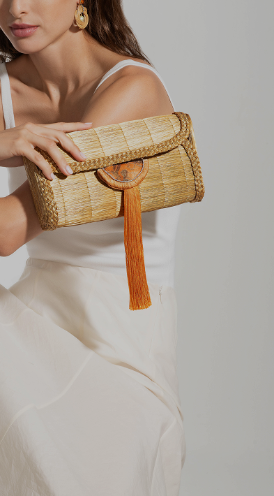 Woman holding a woven clutch bag with a plain background